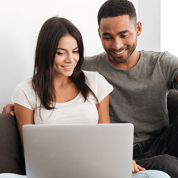 Happy couple on the couch using laptop